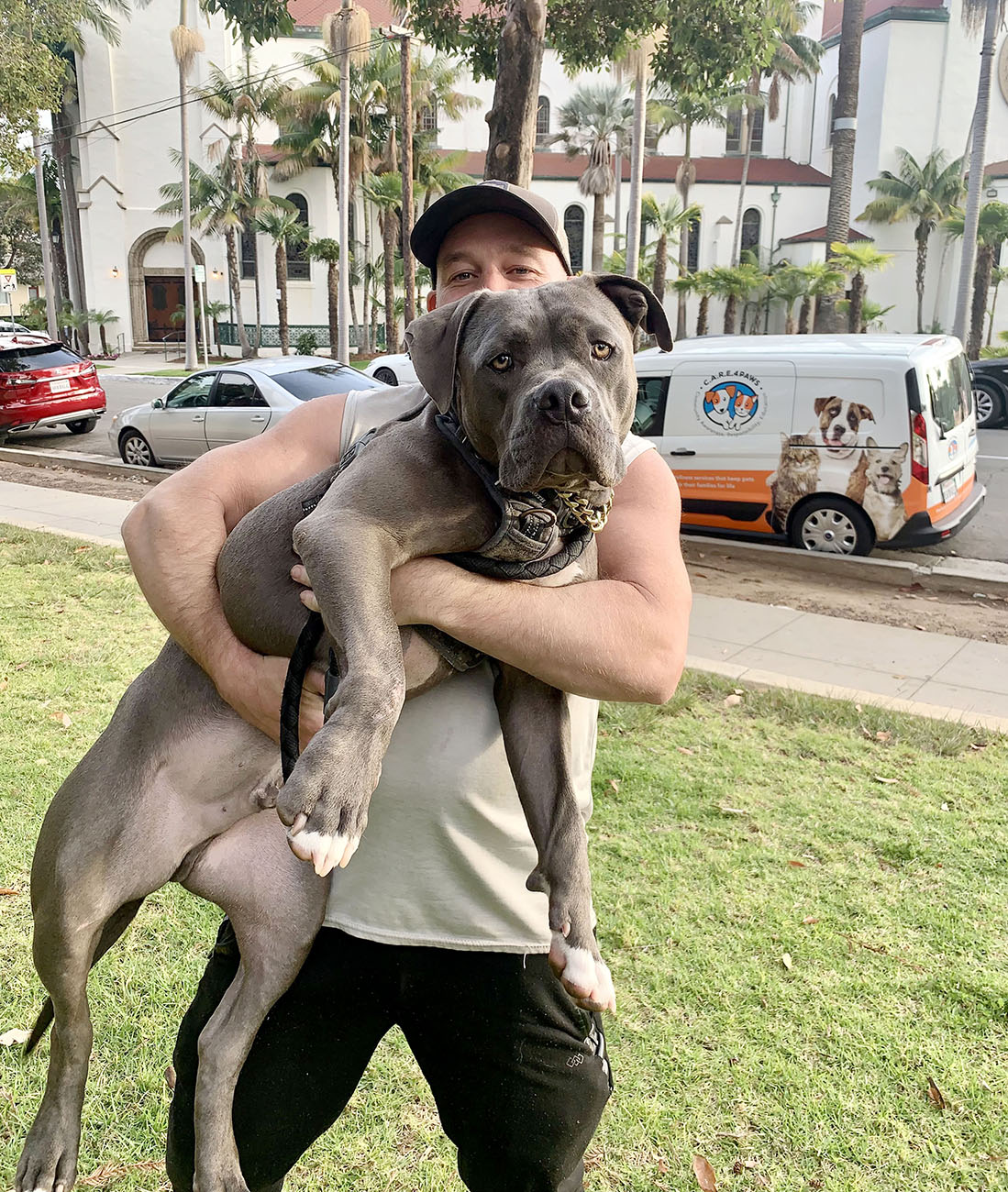 Man hold his large grey dog in the air for a picture