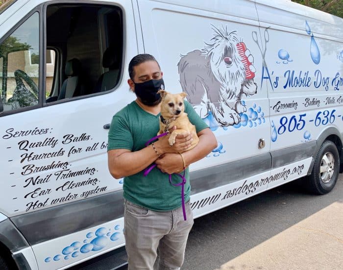 Man holding dog in front of a mobile grooming unit