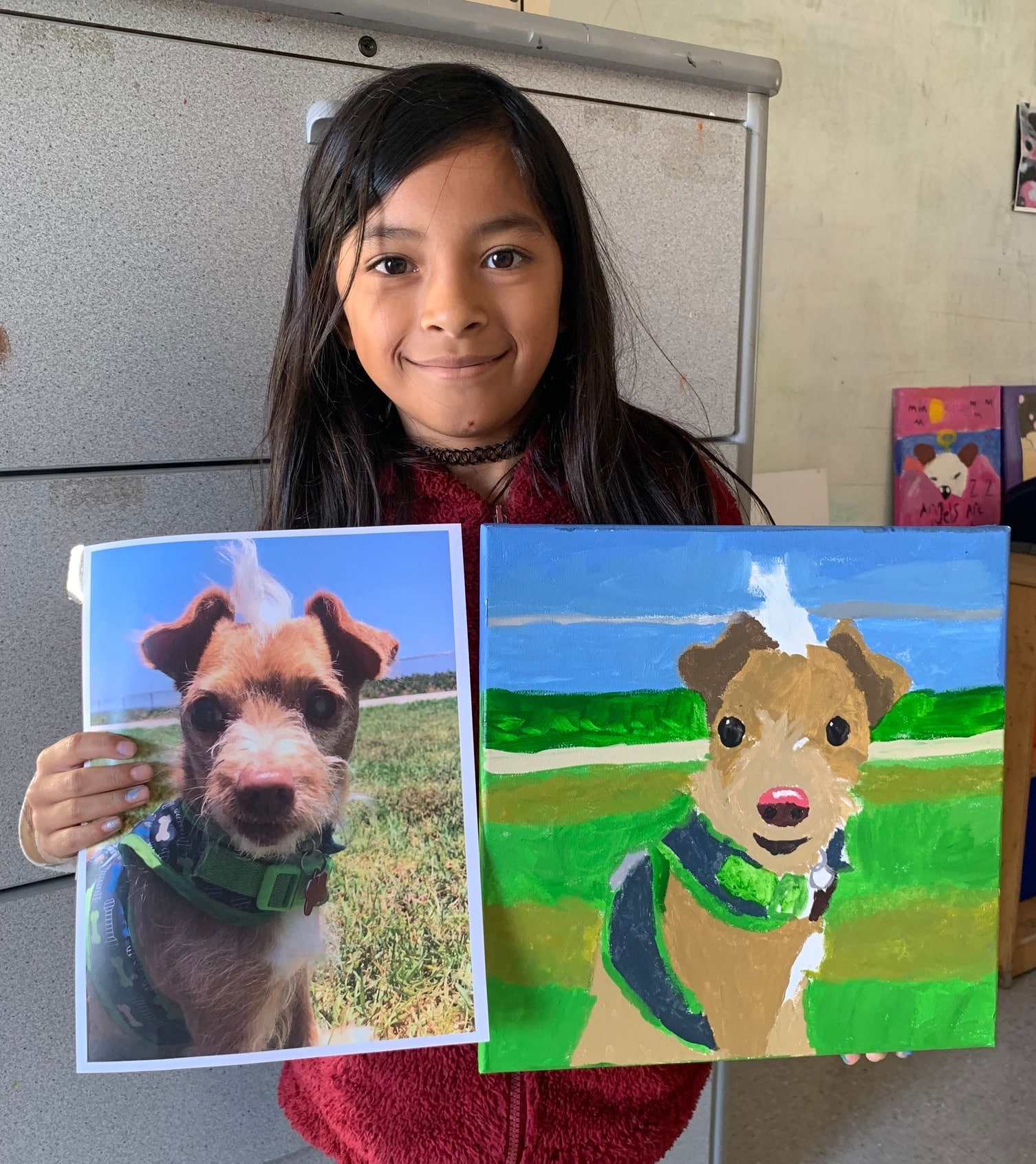 Girl holding a picture of the pet and the pet portrait she made from it