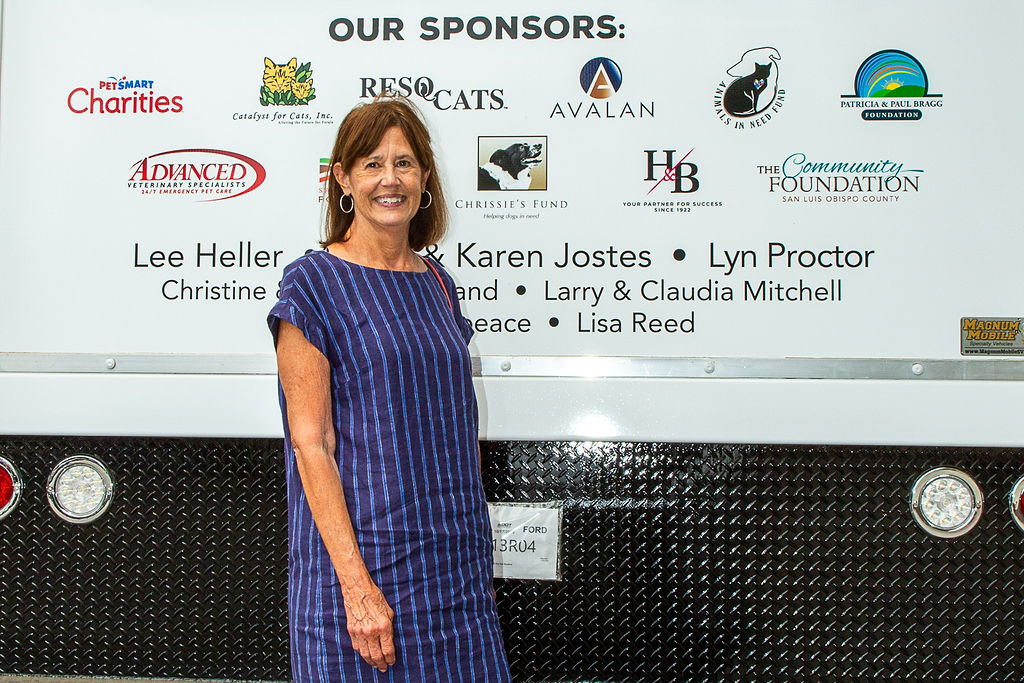 Lyn Proctor standing in front of the list of sponsors on the back of our mobile pet wellness clinic