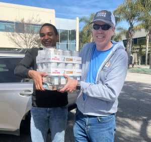 A volunteer and a community member with canned cat and dog food for the pet food drive thru at Decker's Brand in Goleta