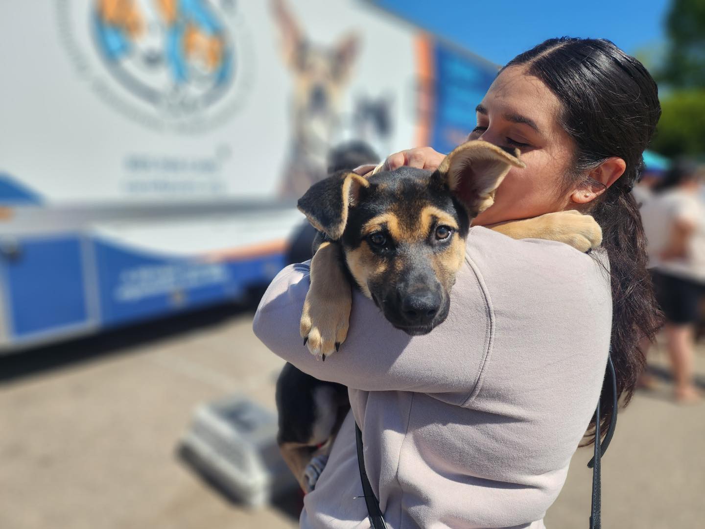 C.A.R.E.4Paws Courtesy Photo 1 A lady holding her large black with brown highlights in front of the mobile clinic