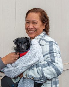 Lady holding dog bundled up in a grey blanket