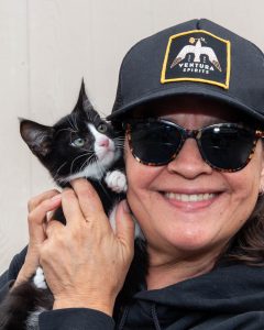 Lady holding black and white cat close to her face