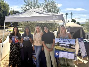 Event attendees and staff at Paws & Pours under the C.A.R.E.4Paws booth