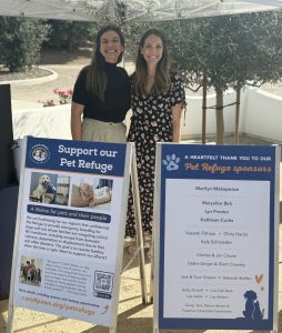 Julia and another attendee posing behind two sandwich boards with information about C.A.R.E.4Paws' future Pet Refuge