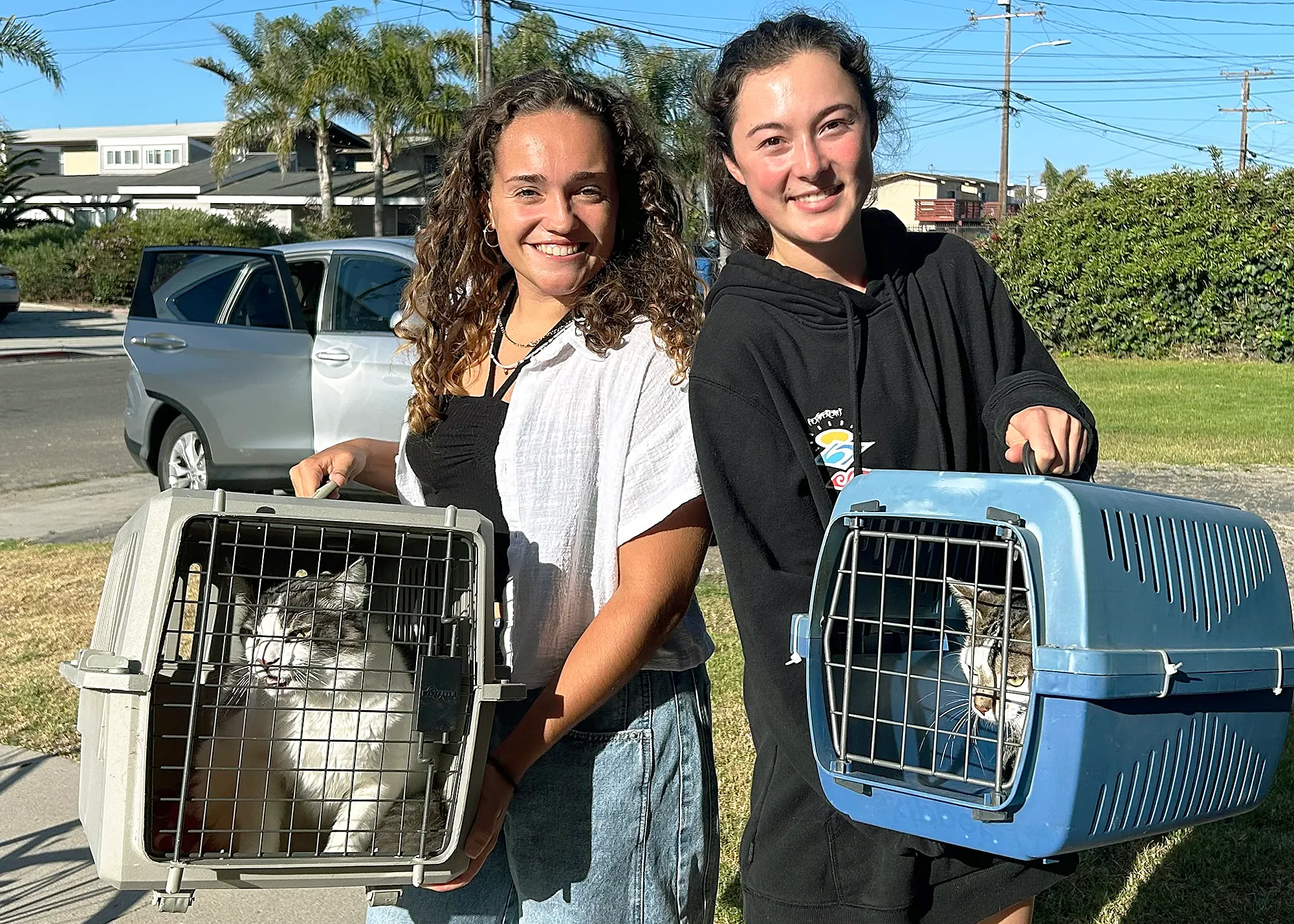 New Time SLO boarding for struggling pet families Two girls holding different types of pet cages each holding one cat