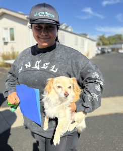 Lady smiling and holding a medium sized long haired dog
