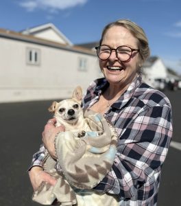 A very happy lady holding her small white senior dog after receiving pet wellness