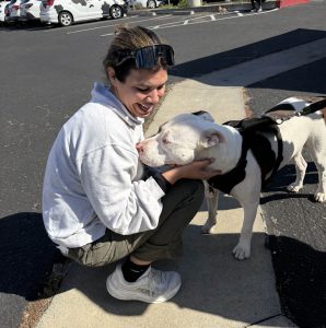 Staff member, Samantha Ranis, greeting a furry white dog at the pet wellness clinic