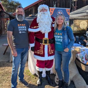 Staff member Libby Williams-Cabral with her husband posing with Santa Claus