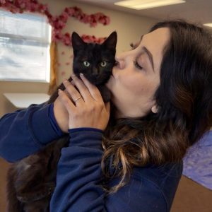 Staff member snuggling a black cat