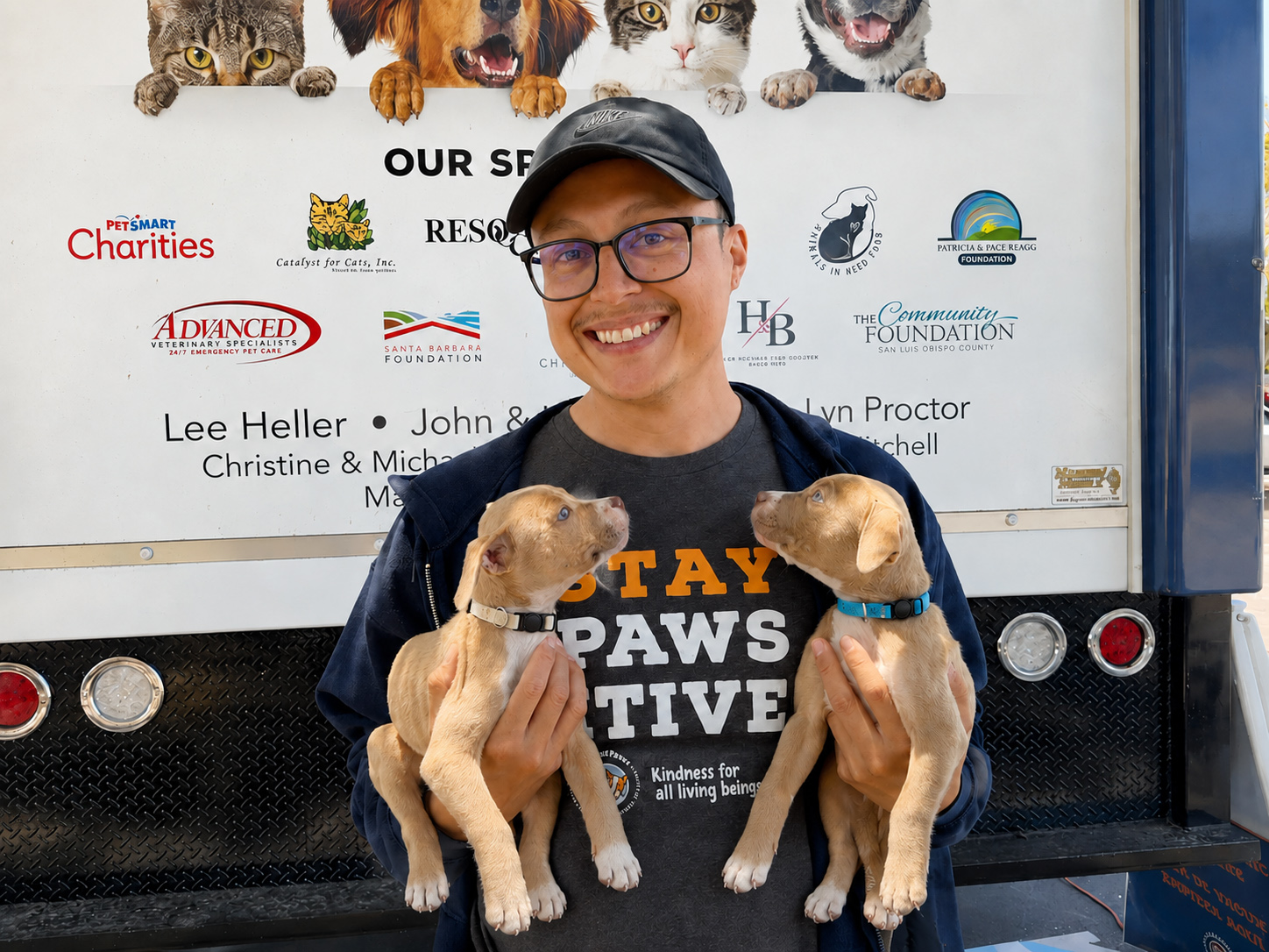 C.A.R.E.4Paws team member Alberto Beas at a pet wellness clinic holding two puppies who are looking up at him