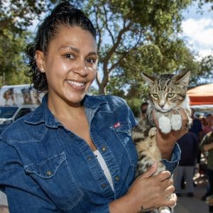 A happy client smiling with her cat held securely at C.A.R.E.4Paws Mobile Pet Wellness Clinic